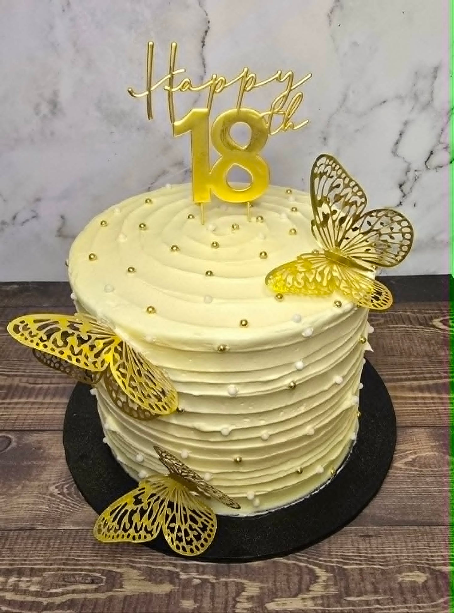 White Cake with gold sugar balls and gold plastic butterflies