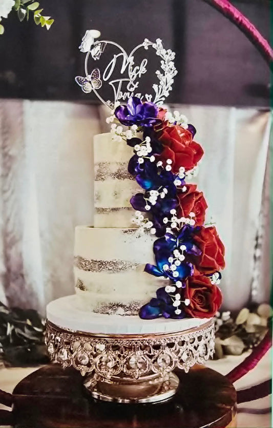 2 tier semi naked wedding cake with red and purple flowers.