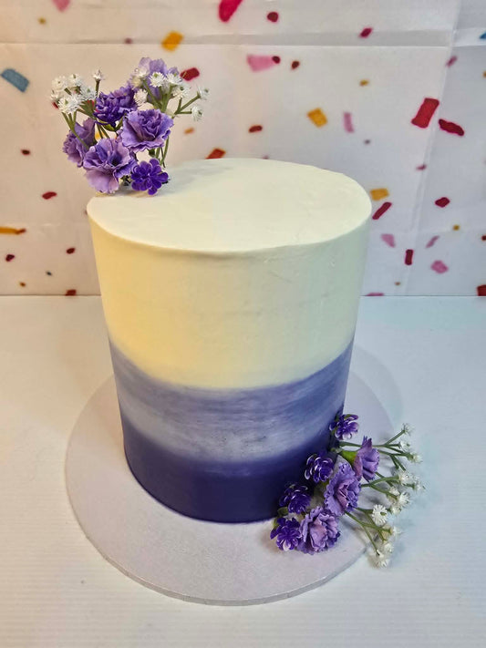 Ombre purple cake with purple flowers.