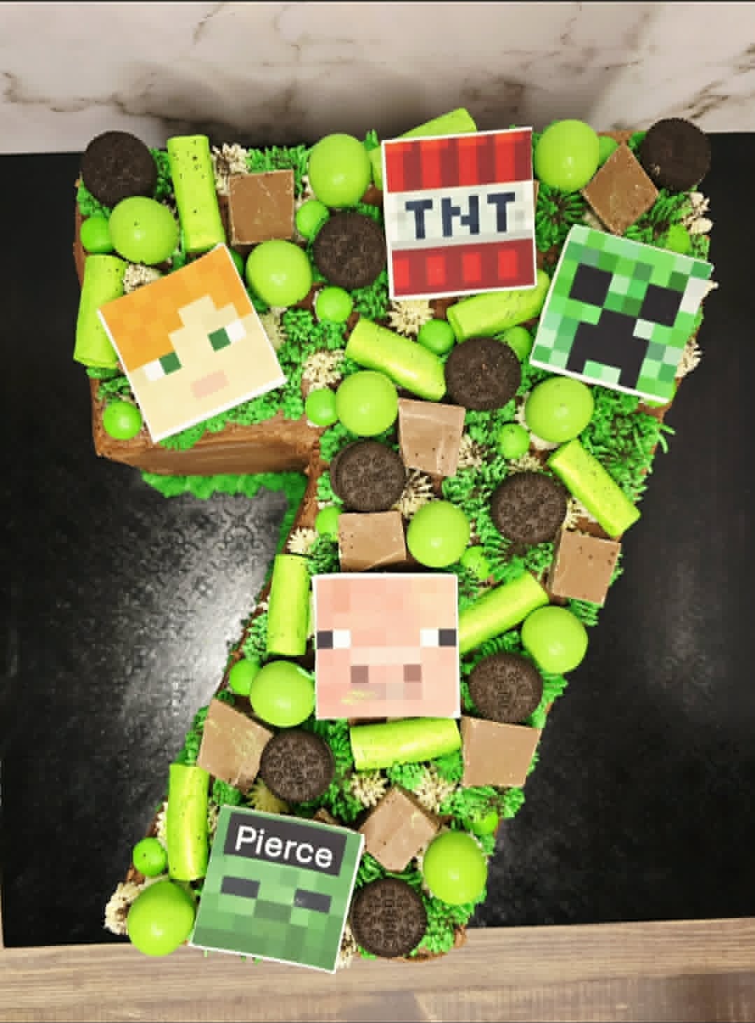 Number 7 shaped cake with Minecraft-themed decorations on a green background
