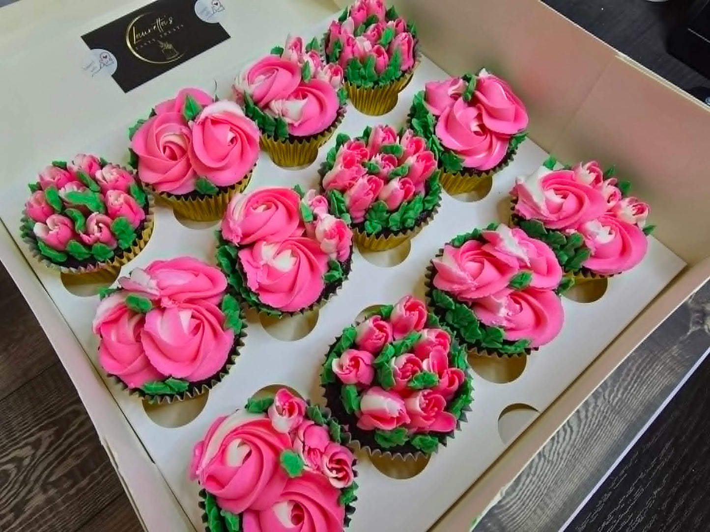 Decorative cupcakes with pink and green frosting in a box