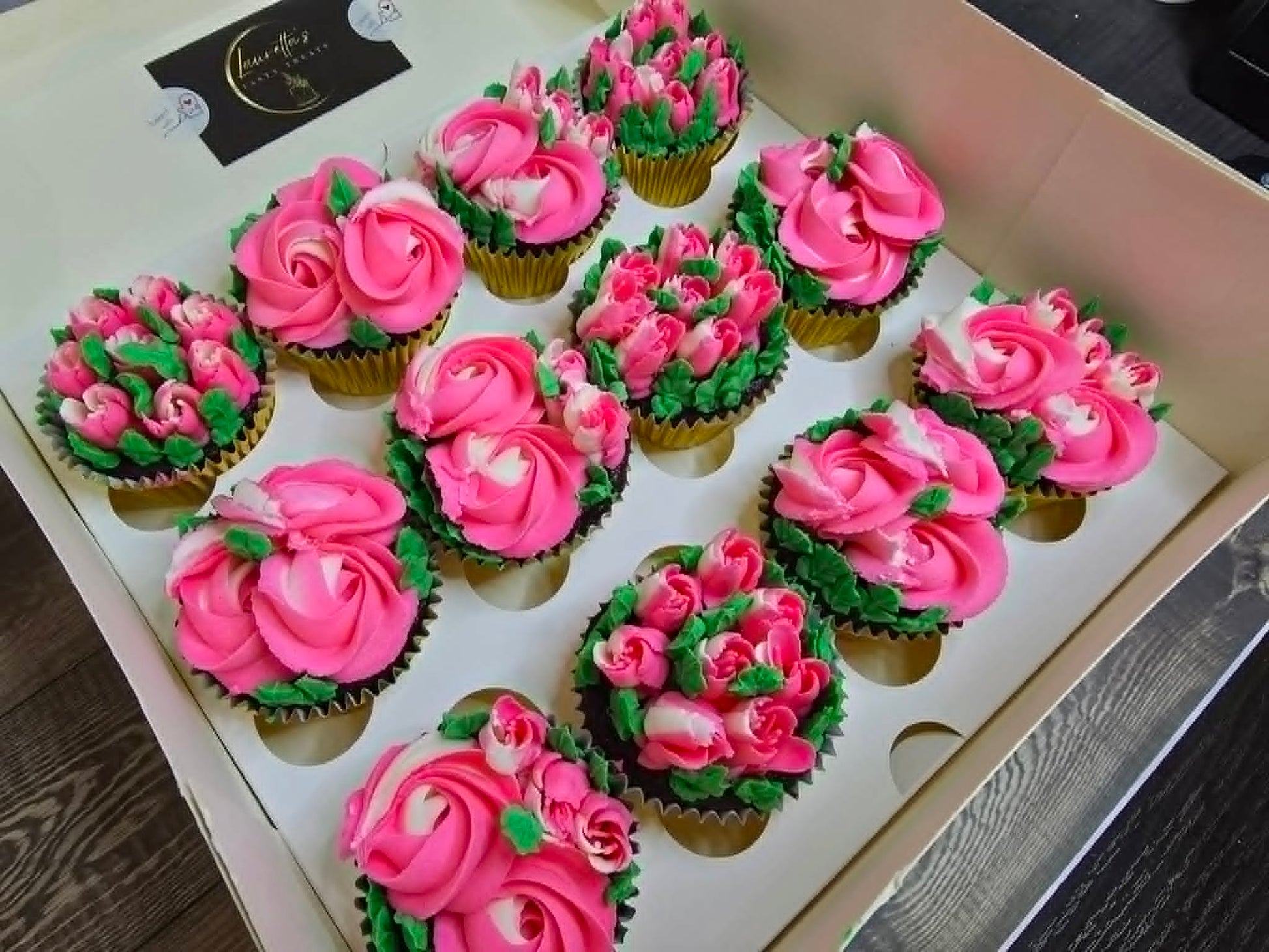 Decorative cupcakes with pink and green frosting in a box