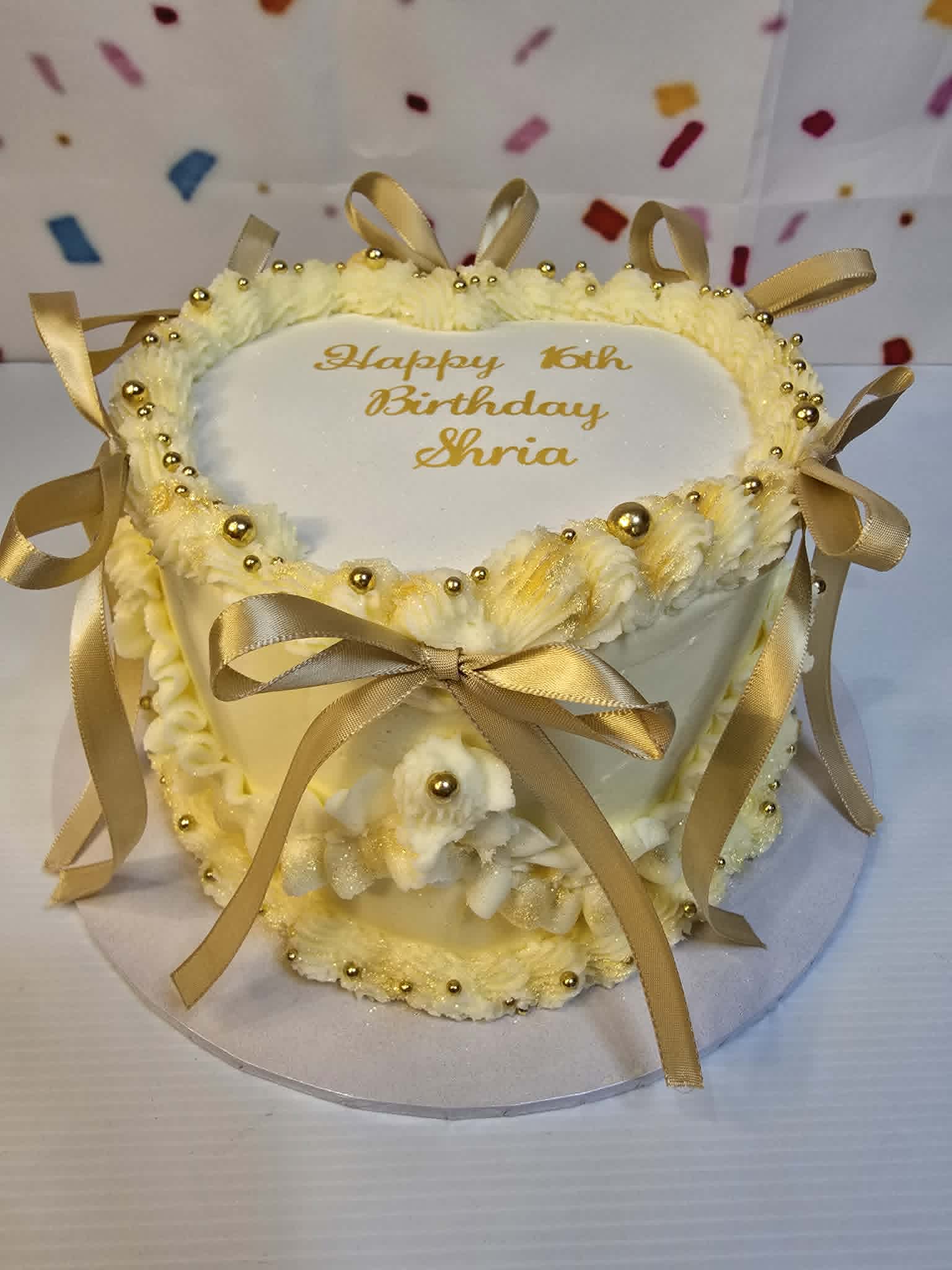 Decorative birthday cake with gold ribbons on a white background